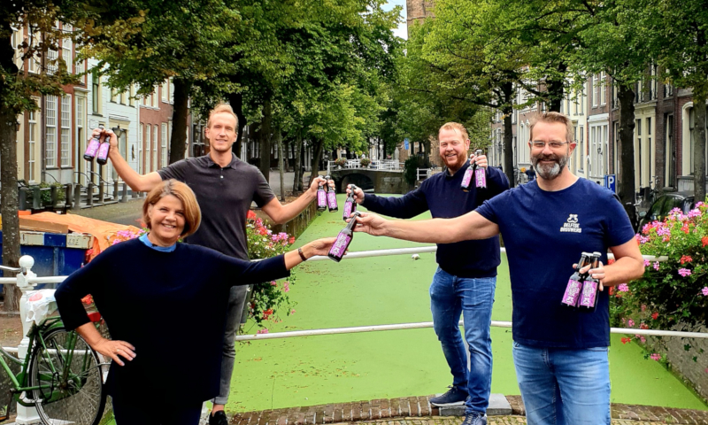 Burgermeester Marja van Bijsterveldt van Delft die het eerste flesje bier in ontvangst nam, Sander Arkenbout (Delfts Brouwhuis), Roland Dijkman (De Delft) en John Brus (Delftse Brouwers) voor een gracht in Delft